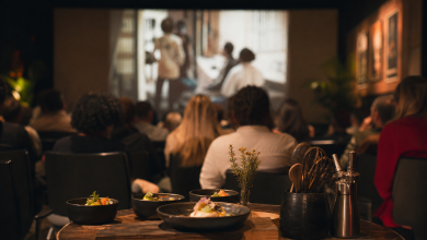 Público acompanha sessão de cinema em espaço cultural com mesa de degustação em primeiro plano