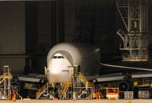 Avião comercial em manutenção dentro de um amplo hangar de aeronaves.