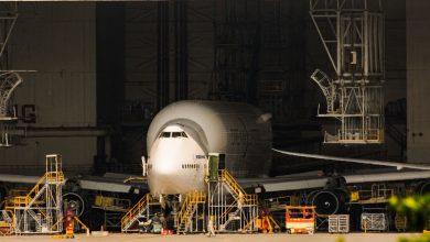 Avião comercial em manutenção dentro de um amplo hangar de aeronaves.