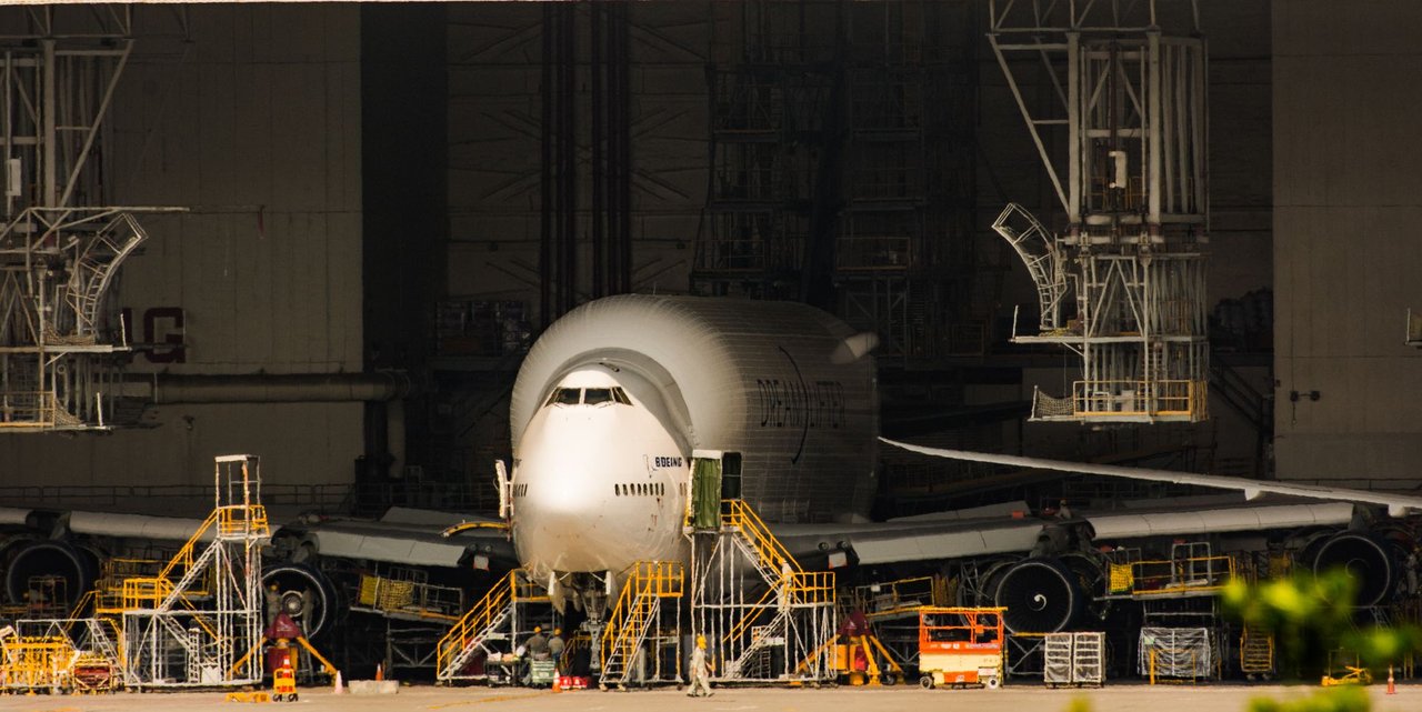 Avião comercial em manutenção dentro de um amplo hangar de aeronaves.