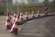Fileira de cones de trânsito sinaliza uma área de obras em uma estrada.