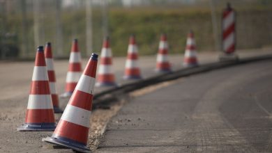 Fileira de cones de trânsito sinaliza uma área de obras em uma estrada.