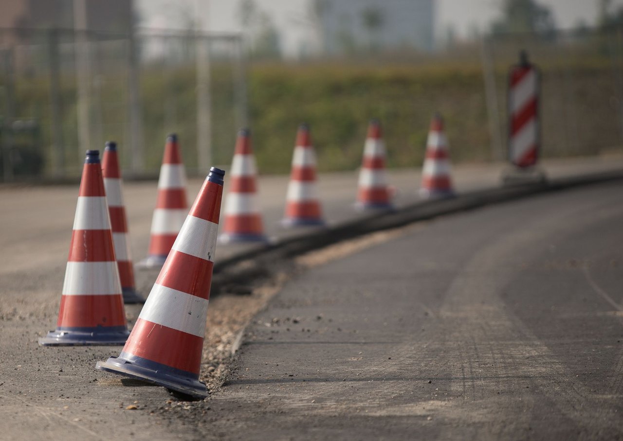 Fileira de cones de trânsito sinaliza uma área de obras em uma estrada.
