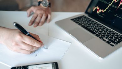 Mãos analisam dados financeiros em uma mesa com notebook e calculadora.